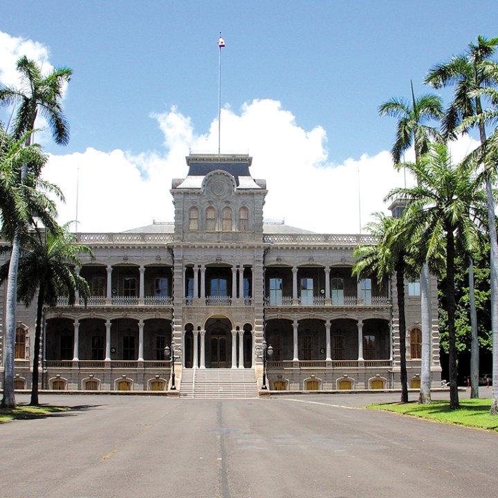 a clock tower in front of Iolani Palace