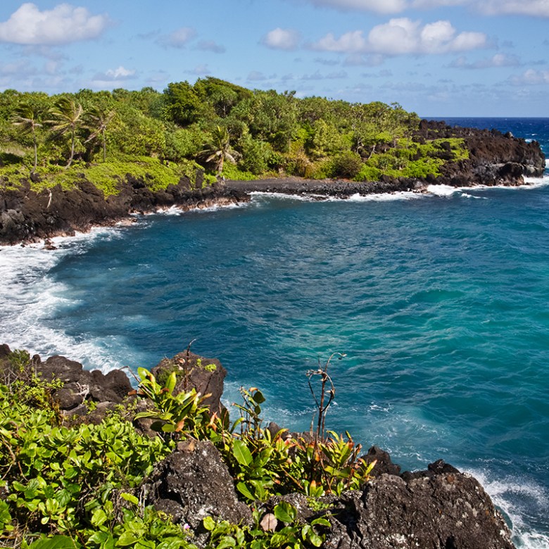 a group of people on a rocky shore next to a body of water