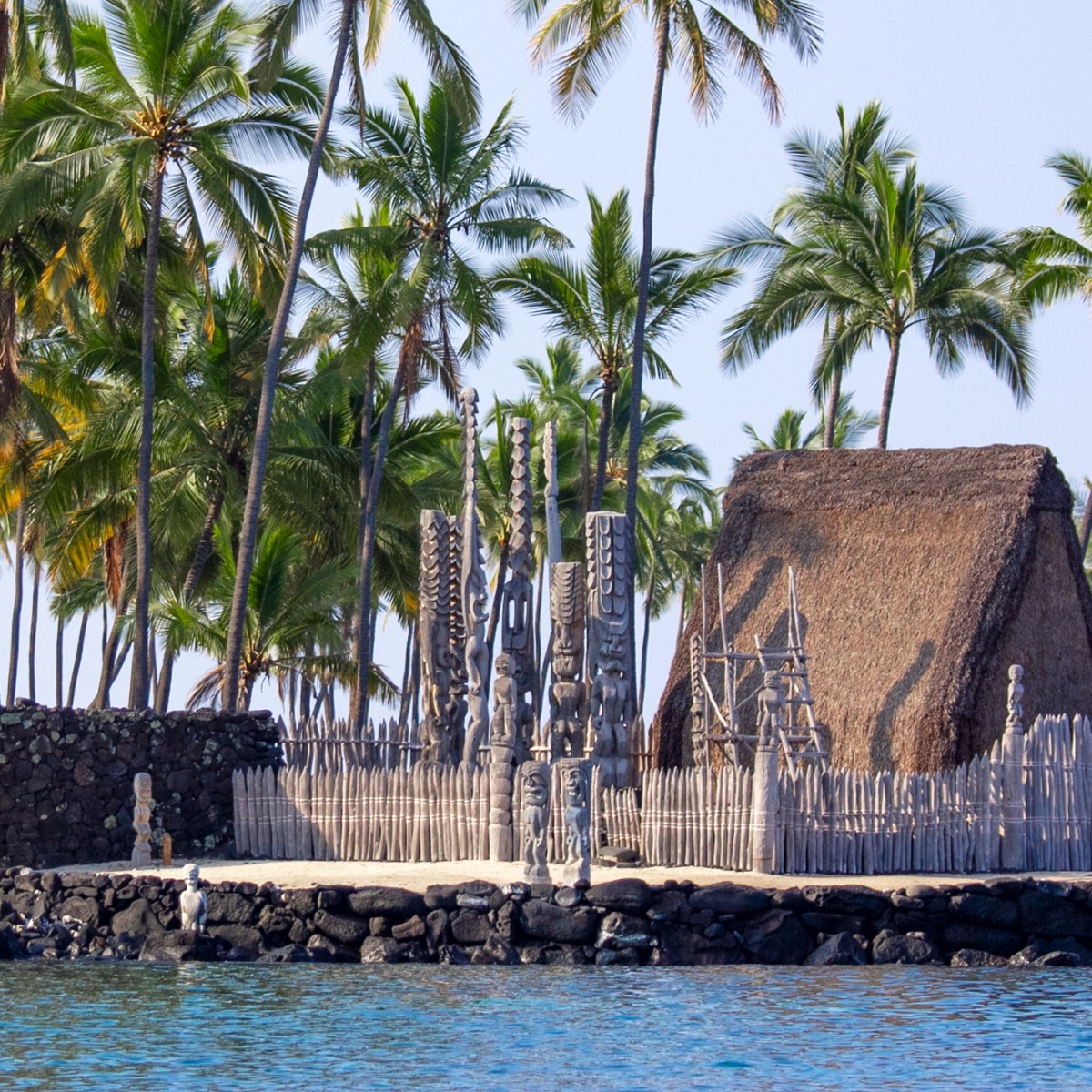 a large stone building with palm trees in front of a body of water