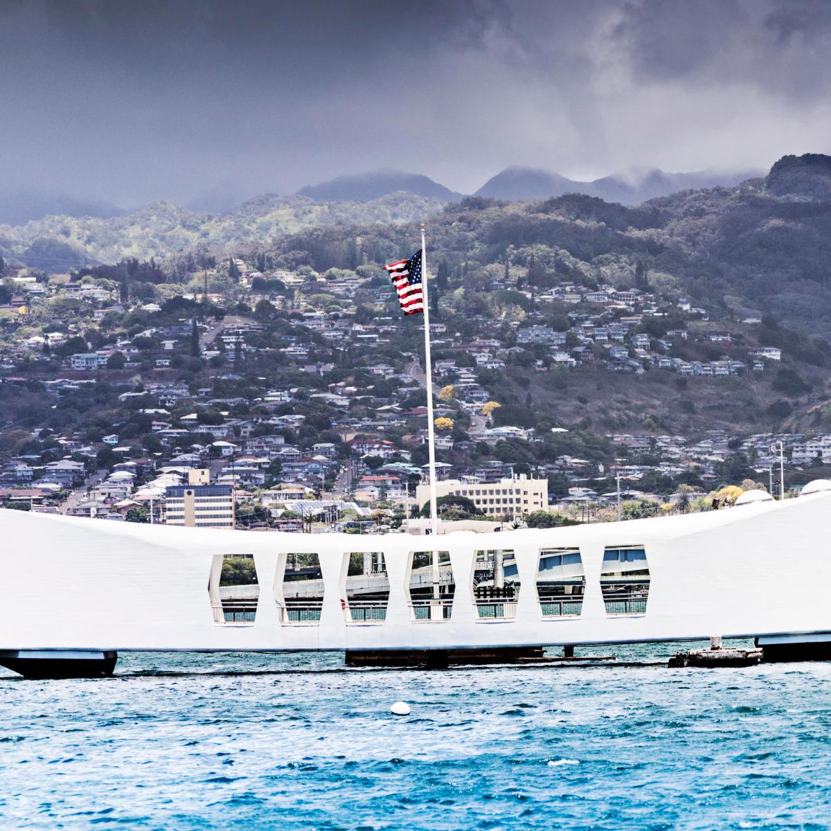 a large ship in a body of water with a mountain in the background